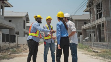 Bir grup mimar ve mühendis birlikte çalışarak konut inşaatının ilerlemesini değerlendirir.