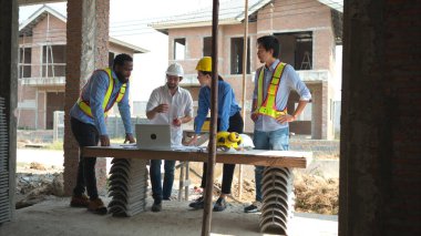 Bir grup mimar ve mühendis birlikte çalışarak konut inşaatının ilerlemesini değerlendirir.