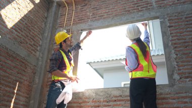 Mimarlar ve mühendisler, konut inşaatının ilerlemesini değerlendirmek için birlikte çalışırlar.