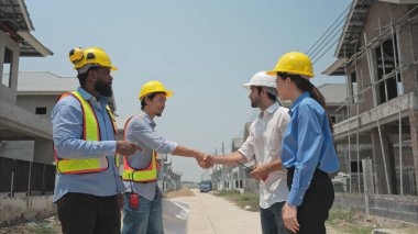 Bir grup mimar ve mühendis birlikte çalışarak konut inşaatının ilerlemesini değerlendirir.