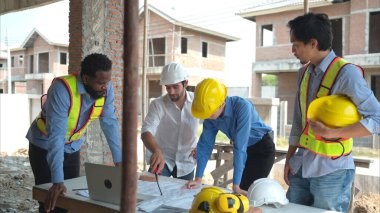 Bir grup mimar ve mühendis birlikte çalışarak konut inşaatının ilerlemesini değerlendirir.