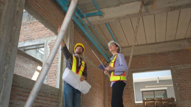 Mimarlar ve mühendisler, konut inşaatının ilerlemesini değerlendirmek için birlikte çalışırlar.