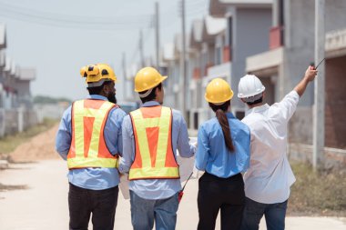 Bir grup mimar ve mühendis birlikte çalışarak konut inşaatının ilerlemesini değerlendirir.