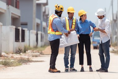 Bir grup mimar ve mühendis birlikte çalışarak konut inşaatının ilerlemesini değerlendirir.