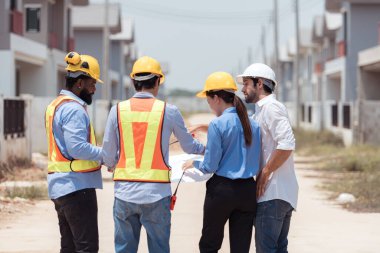 Bir grup mimar ve mühendis birlikte çalışarak konut inşaatının ilerlemesini değerlendirir.