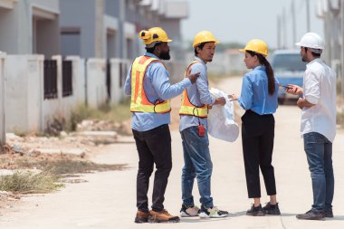 Bir grup mimar ve mühendis birlikte çalışarak konut inşaatının ilerlemesini değerlendirir.
