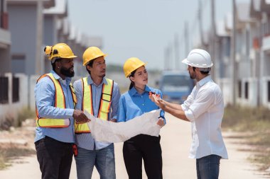 Bir grup mimar ve mühendis birlikte çalışarak konut inşaatının ilerlemesini değerlendirir.