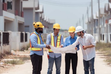Bir grup mimar ve mühendis birlikte çalışarak konut inşaatının ilerlemesini değerlendirir.