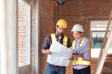 Mimarlar ve mühendisler, konut inşaatının ilerlemesini değerlendirmek için birlikte çalışırlar.
