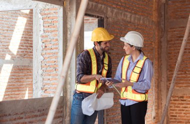 Mimarlar ve mühendisler, konut inşaatının ilerlemesini değerlendirmek için birlikte çalışırlar.