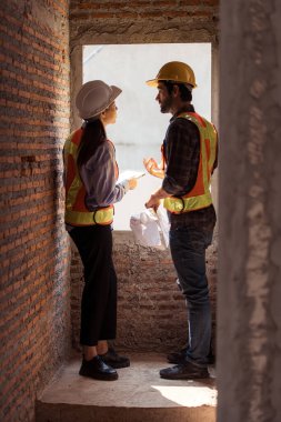 Mimarlar ve mühendisler, konut inşaatının ilerlemesini değerlendirmek için birlikte çalışırlar.