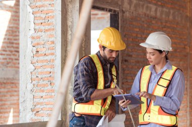 Mimarlar ve mühendisler, konut inşaatının ilerlemesini değerlendirmek için birlikte çalışırlar.