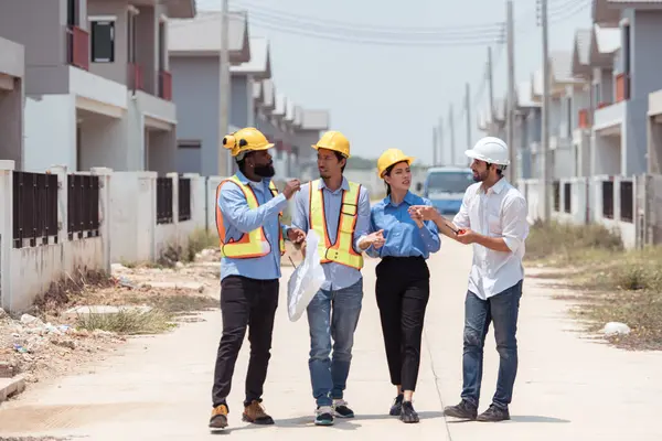 Bir grup mimar ve mühendis birlikte çalışarak konut inşaatının ilerlemesini değerlendirir.