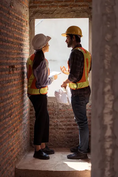 Mimarlar ve mühendisler, konut inşaatının ilerlemesini değerlendirmek için birlikte çalışırlar.