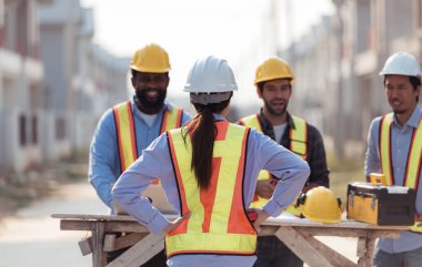 Bir grup mimar ve mühendis birlikte çalışarak konut inşaatının ilerlemesini değerlendirir.