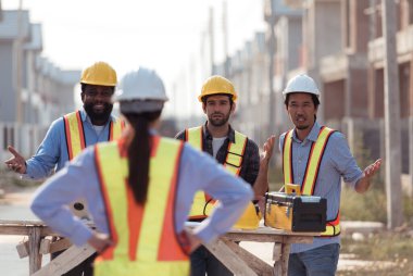 Bir grup mimar ve mühendis birlikte çalışarak konut inşaatının ilerlemesini değerlendirir.