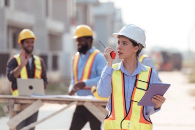 Mühendislerin portresi konut inşaatının ilerlemesini değerlendirmek için birlikte çalışıyor.
