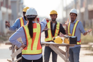 Bir grup mimar ve mühendis birlikte çalışarak konut inşaatının ilerlemesini değerlendirir.