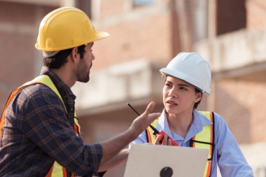 Mimarlar ve mühendisler, konut inşaatının ilerlemesini değerlendirmek için birlikte çalışırlar.
