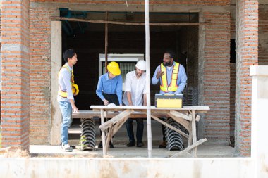 Bir grup mimar ve mühendis birlikte çalışarak konut inşaatının ilerlemesini değerlendirir.