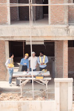Bir grup mimar ve mühendis birlikte çalışarak konut inşaatının ilerlemesini değerlendirir.