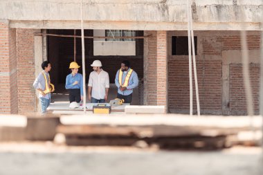 Bir grup mimar ve mühendis birlikte çalışarak konut inşaatının ilerlemesini değerlendirir.