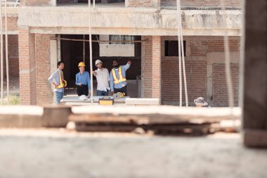 Bir grup mimar ve mühendis birlikte çalışarak konut inşaatının ilerlemesini değerlendirir.