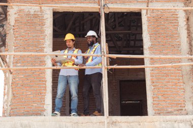 Mimarlar ve mühendisler, konut inşaatının ilerlemesini değerlendirmek için birlikte çalışırlar.