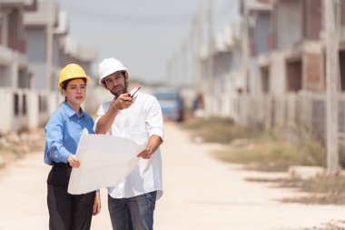 Mimarlar ve mühendisler, konut inşaatının ilerlemesini değerlendirmek için birlikte çalışırlar.