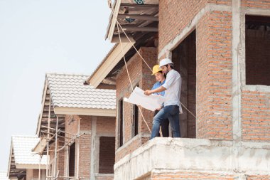 Mimarlar ve mühendisler, konut inşaatının ilerlemesini değerlendirmek için birlikte çalışırlar.