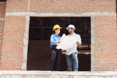 Mimarlar ve mühendisler, konut inşaatının ilerlemesini değerlendirmek için birlikte çalışırlar.