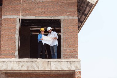 Mimarlar ve mühendisler, konut inşaatının ilerlemesini değerlendirmek için birlikte çalışırlar.