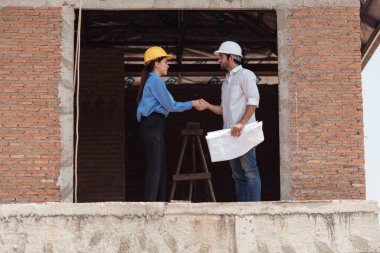 Mimarlar ve mühendisler, konut inşaatının ilerlemesini değerlendirmek için birlikte çalışırlar.