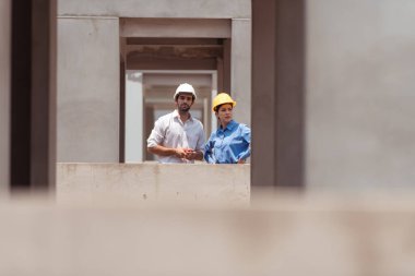 Mimarlar ve mühendisler, konut inşaatının ilerlemesini değerlendirmek için birlikte çalışırlar.