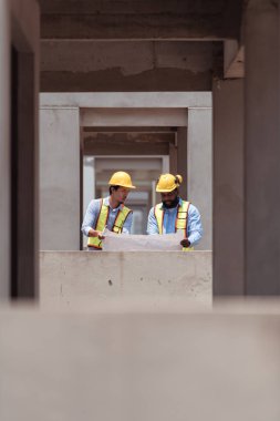 Mimarlar ve mühendisler, konut inşaatının ilerlemesini değerlendirmek için birlikte çalışırlar.