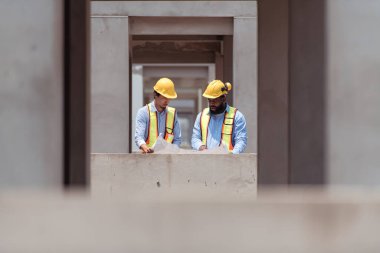 Mimarlar ve mühendisler, konut inşaatının ilerlemesini değerlendirmek için birlikte çalışırlar.