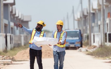 Mimarlar ve mühendisler, konut inşaatının ilerlemesini değerlendirmek için birlikte çalışırlar.