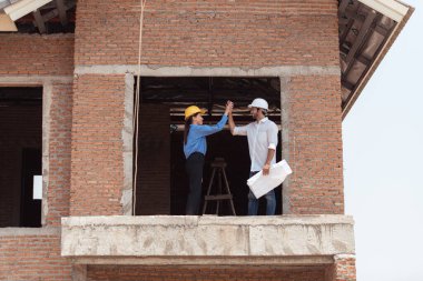 Mimarlar ve mühendisler, konut inşaatının ilerlemesini değerlendirmek için birlikte çalışırlar.