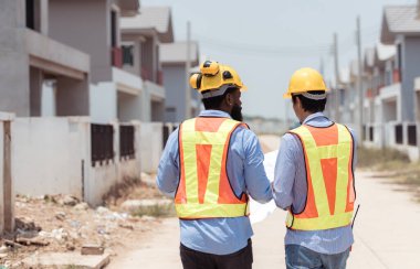 Mimarlar ve mühendisler, konut inşaatının ilerlemesini değerlendirmek için birlikte çalışırlar.