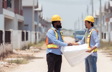 Mimarlar ve mühendisler, konut inşaatının ilerlemesini değerlendirmek için birlikte çalışırlar.