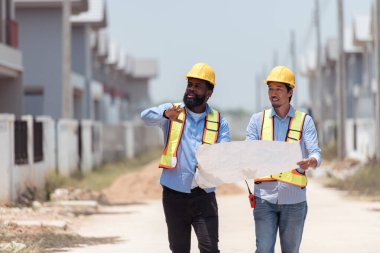 Mimarlar ve mühendisler, konut inşaatının ilerlemesini değerlendirmek için birlikte çalışırlar.