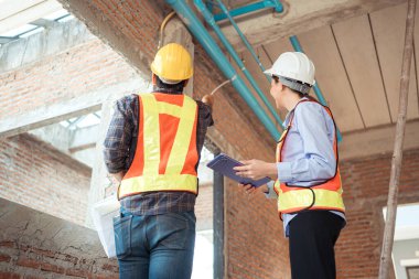 Mimarlar ve mühendisler, konut inşaatının ilerlemesini değerlendirmek için birlikte çalışırlar.