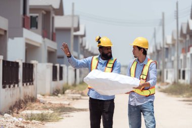 Mimarlar ve mühendisler, konut inşaatının ilerlemesini değerlendirmek için birlikte çalışırlar.