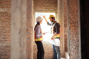 Mimarlar ve mühendisler, konut inşaatının ilerlemesini değerlendirmek için birlikte çalışırlar.