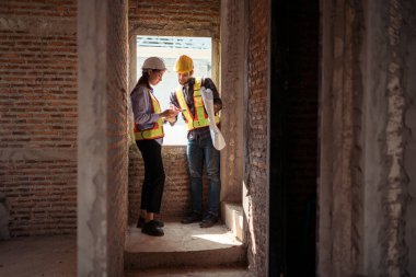 Mimarlar ve mühendisler, konut inşaatının ilerlemesini değerlendirmek için birlikte çalışırlar.