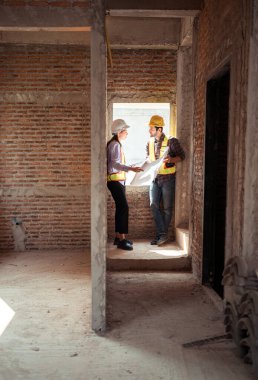 Mimarlar ve mühendisler, konut inşaatının ilerlemesini değerlendirmek için birlikte çalışırlar.