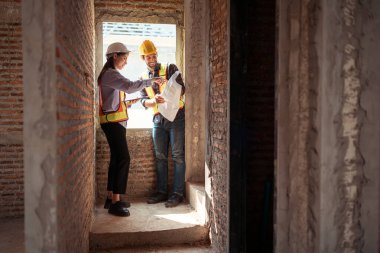 Mimarlar ve mühendisler, konut inşaatının ilerlemesini değerlendirmek için birlikte çalışırlar.