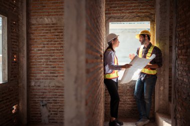 Mimarlar ve mühendisler, konut inşaatının ilerlemesini değerlendirmek için birlikte çalışırlar.