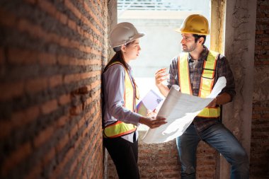 Mimarlar ve mühendisler, konut inşaatının ilerlemesini değerlendirmek için birlikte çalışırlar.