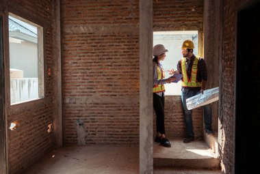 Mimarlar ve mühendisler, konut inşaatının ilerlemesini değerlendirmek için birlikte çalışırlar.